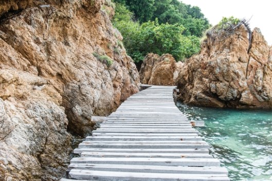 Old vintage wooden walking bridge over sea water